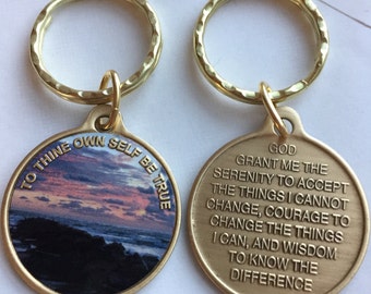 May include: Gold-tone keychain with two round metal tags. One tag features a sunset over the ocean with the text "To thine own self be true". The other tag has the text "God grant me the serenity to accept the things I cannot change, courage to change the things I can, and wisdom to know the difference."