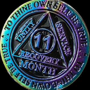 May include: A black metal coin with a rainbow iridescent finish. The coin features a triangle with the words "Unity", "Recovery Month", and "Service" inscribed around the triangle. The number "11" is in the center of the triangle. The words "Be true to thine own self be true to thine own self" are inscribed around the outer edge of the coin.