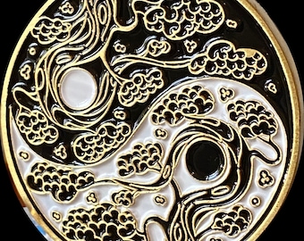 May include: A gold-colored metal yin yang symbol with a black and white design. The symbol features a stylized tree with branches that intertwine and form the yin yang shape. The tree is outlined in gold and has black and white leaves.