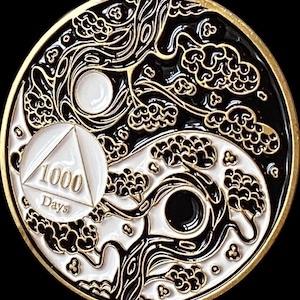 May include: A round, black, white, and gold coin featuring a Yin and Yang design with stylized clouds and trees. A white circle with a triangle and the text "1000 Days" is on the left side of the coin. The coin has a gold border.