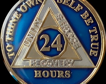 Peut inclure: Une pièce de monnaie en or et en argent avec un fond bleu. La pièce présente un triangle avec les mots "Unité, Service, Récupération" inscrits sur les côtés. Le centre de la pièce a un cercle avec le nombre "24" et les mots "To Thine Own Self Be True" et "24 Hours" sont inscrits autour du triangle.