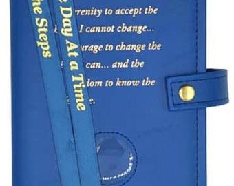 Peut inclure: Un journal en cuir bleu avec une inscription dorée qui dit "One Day At a Time" et "Grant me the serenity to accept the things I cannot change... the courage to change the things I can... and the wisdom to know the difference." Le journal a un ruban bleu en guise de marque-page et un fermoir doré.
