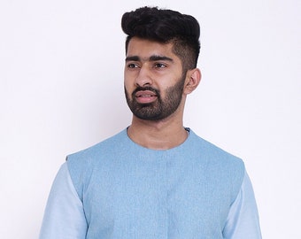 May include: A light blue waistcoat with a mandarin collar and two pockets. The waistcoat is made of a textured fabric and is worn over a light blue shirt.