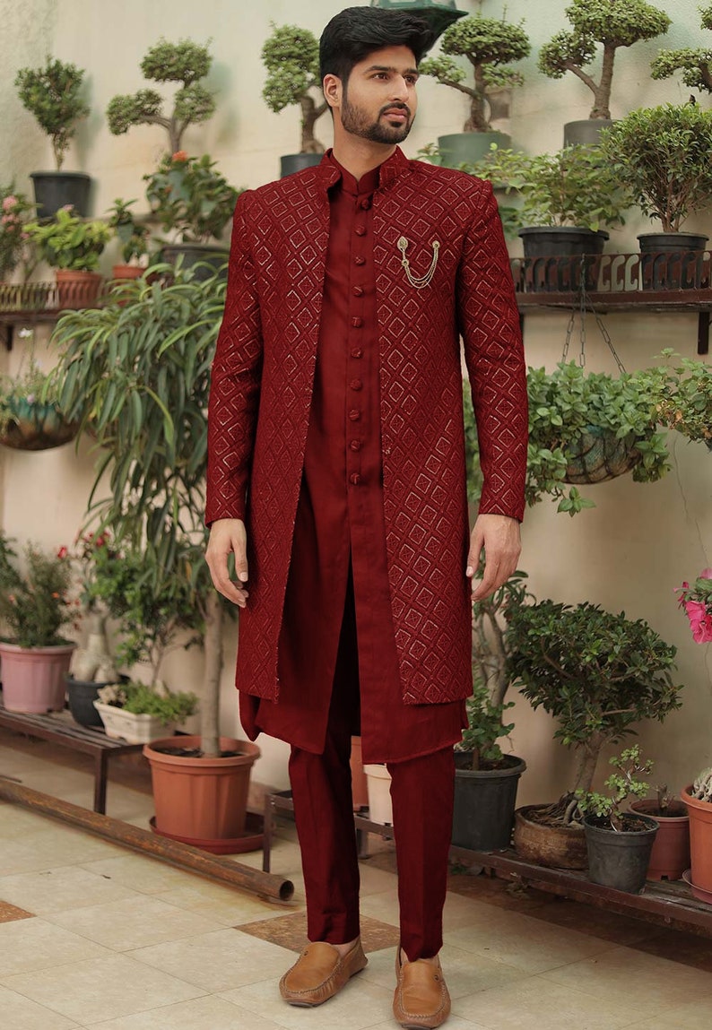 May include: A maroon long-sleeved kurta with a geometric pattern and a matching pair of pants. The kurta has a mandarin collar and a button closure. The man is wearing brown leather loafers.