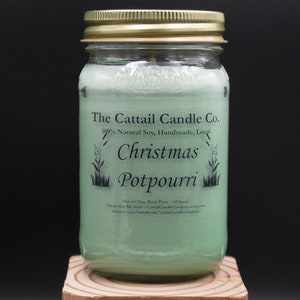May include: A green glass jar candle with a gold lid. The label reads "The Cattail Candle Co. 100% Natural Soy, Handmade, Local Christmas Potpourri".