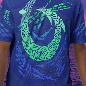 May include: A blue t-shirt with a green and blue fish hook design and the text "MATAU A MAUI". The shirt is covered in a pattern of blue fish.