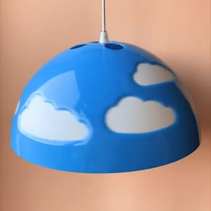 May include: A blue pendant light fixture with white cloud designs. The light has a rounded, dome-like shape and is suspended from a white cord. The clouds are painted on the blue surface.