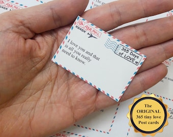 May include: A set of 365 small, white, and blue postcards with a vintage airmail design. Each card features a different love message. The text on the card shown reads "I love you and that is all you really need to know."