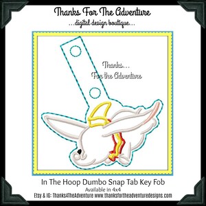 Può includere: Un portachiavi a tema Dumbo bianco con dettagli gialli e rossi. Il portachiavi ha una parte superiore rettangolare con due fori e la scritta "Thanks... For the Adventure". Il design è delineato in verde acqua e su un bordo giallo e blu.