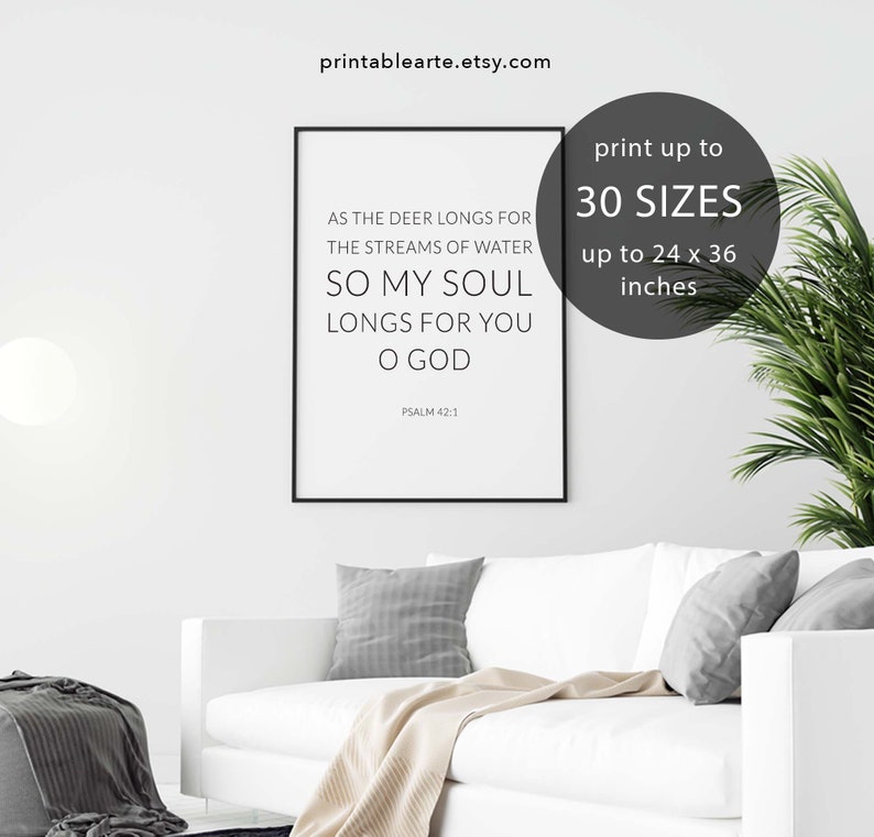 May include: A black and white printable wall art print with the text "As the deer longs for the streams of water, so my soul longs for you O God. Psalm 42:1". The print is framed and displayed on a white couch in a living room setting.