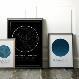 May include: Three framed star charts with black and white designs. One chart is black with a white star map and text. Another is a blue star map with text. The third is a blue star map with text. The frames are black and gold.