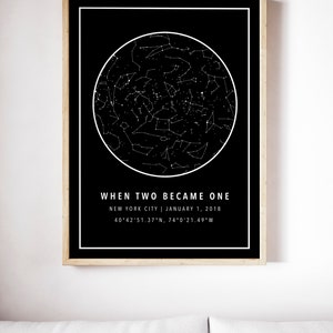 May include: A framed black and white print featuring a star map within a white circular outline. The text "WHEN TWO BECAME ONE" is above the location and date: New York City, January 1, 2018, with coordinates. The frame is a light wood color.