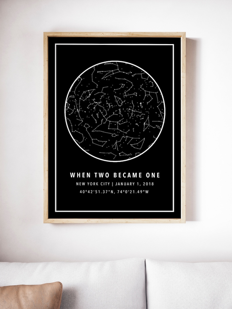 May include: A framed black and white print featuring a star map within a white circular outline. The text "WHEN TWO BECAME ONE" is above the location and date: New York City, January 1, 2018, with coordinates. The frame is a light wood color.