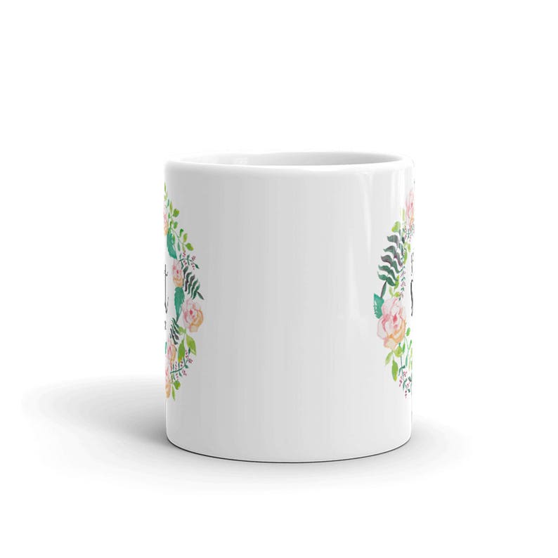 May include: White ceramic mug with a floral design featuring pink and peach flowers and green leaves. The text "Just Breathe" is printed on the mug.