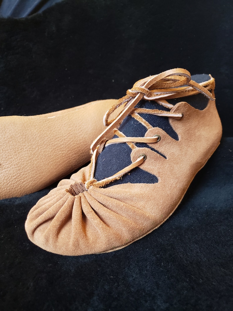 Pode incluir: Sapatos de couro castanho com forro de tecido preto e atacadores. Os sapatos t&ecirc;m uma ponta franzida e uma forma pontiaguda.