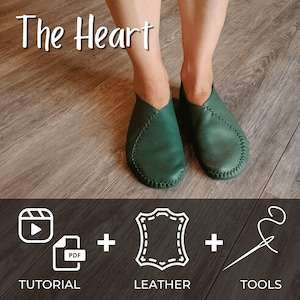 May include: A pair of green leather slippers with a pointed toe and a stitched seam around the edge. The slippers are on a wooden floor. The text "The Heart" is at the top of the image. Below the slippers are three icons: a video camera, a PDF file, and a needle and thread. The text "TUTORIAL", "LEATHER", and "TOOLS" are below the icons.