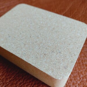 May include: A rectangular cork block with a light brown color and a slightly rough texture.