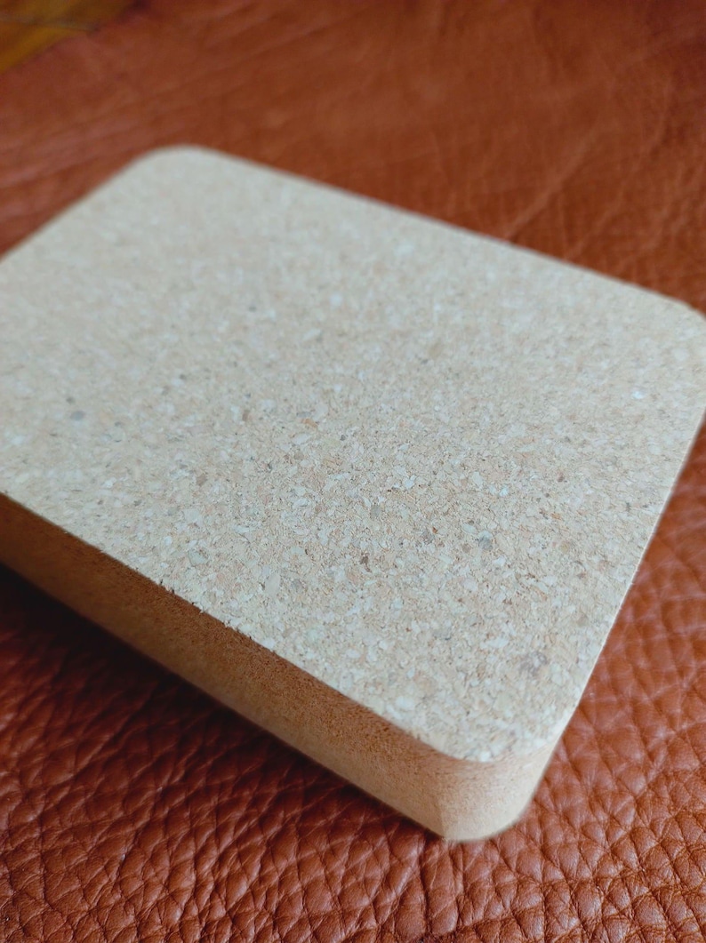 May include: A rectangular cork block with a light brown color and a slightly rough texture.