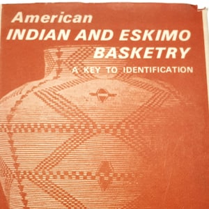 Puede incluir: Portada del libro "American Indian and Eskimo Basketry" con una ilustración detallada de una cesta tejida. La portada es predominantemente naranja con texto blanco y elementos de diseño. Los autores Charles Miles y Pierre Bovis están listados.