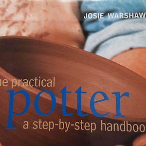 Puede incluir: Primer plano de un cuenco de cerámica marrón con el texto "the practical Potter" y "a step-by-step handbook" en blanco y azul. El nombre del autor, "JOSIE WARSHAW", es visible en la parte superior. La imagen sugiere una guía de cerámica.