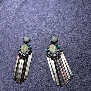 May include: A pair of gold dangle earrings with a light green and blue gemstone and crystal accents.