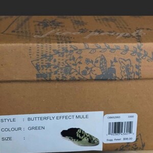 May include: A box for a pair of green butterfly effect mule shoes by Free People. The box has a floral pattern and the text "STYLE: BUTTERFLY EFFECT MULE", "COLOUR: GREEN", "SIZE", "08652993", "3300", "Sugg. Retail $98.00" is printed on the box.