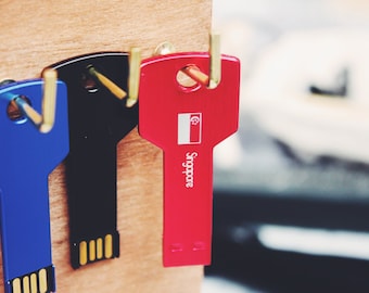 May include: Three key-shaped USB drives, one red, one black, and one blue. The red drive has the Singapore flag and the word "Singapore" printed on it.