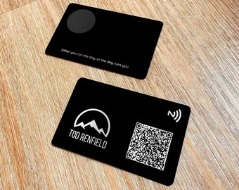 May include: Black business card with a silver mountain logo and the text "Tod Renfield". The card also has a QR code and a silver symbol with a wave and a "Z" in the top right corner. The back of the card is black with the text "Either you run the day, or the day runs you".