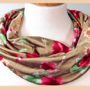 Könnte beinhalten: Ein brauner Infinity-Schal mit einem Blumendruck mit roten, rosa, weißen und orangefarbenen Blumen.