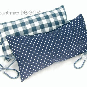 以下が含まれることがあります： 青と白のチェック柄と青と白のドット柄の装飾的な枕が2つ。枕には透明なプラスチック製の留め具が付いた灰色の紐が付いています。