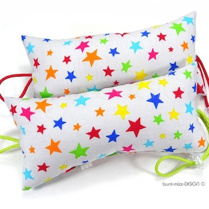 Op de afbeelding: Twee witte rechthoekige kussens met kleurrijke sterpatronen en trekkoord sluitingen. De kussens zijn gemaakt van stof en hebben een witte achtergrond met veelkleurige sterren.