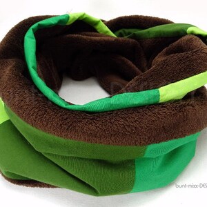 May include: A brown fleece-lined neck warmer with green and lime green stripes. The neck warmer is folded in half and the fleece lining is visible.