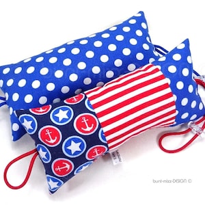 Könnte beinhalten: Zwei blaue und rote Stoffkissen mit nautischem Thema. Ein Kissen ist blau mit weißen Punkten und das andere ist blau, rot und weiß mit Ankern und Sternen.