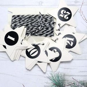 Peut inclure: Kit de calendrier de l'Avent avec des étiquettes en forme d'étoile numérotées de 1 à 25 en noir sur fond crème. Comprend une bobine de ficelle noire et blanche pour l'accrochage. Parfait pour les décomptes de vacances.