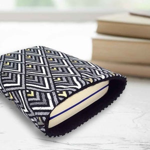 May include: A black and white geometric patterned book cover with a black border. The cover is made of fabric and has a soft, plush texture.