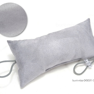 Könnte beinhalten: Ein grauer Samtbeutel mit einem grauen Kordelzug und einem durchsichtigen Plastikverschluss. Der Beutel ist leer und hat eine weiche, plüschige Textur.