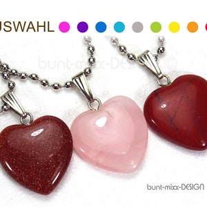 May include: Three heart-shaped pendants on silver chains. The pendants are made of red, pink, and brown stone.