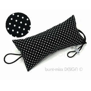 Könnte beinhalten: Ein schwarzer und weißer Türdämpfer mit Punkten und einer schwarzen elastischen Schlaufe. Der Türdämpfer ist wie ein langes Kissen geformt.