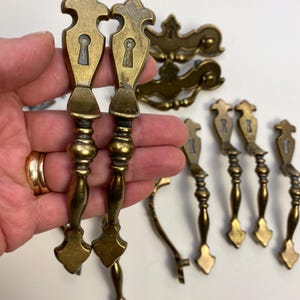 Peut inclure: Un ensemble de dix boutons de cabinet en laiton antique avec un motif de trou de serrure. Les boutons ont un design décoratif et orné et sont en bon état.