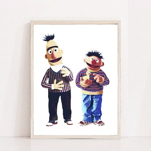May include: A print featuring two Sesame Street characters, Bert and Ernie, standing side-by-side. Bert is wearing a striped shirt and pants, while Ernie is wearing a red and white striped sweater and blue jeans. Ernie is holding a yellow rubber ducky.