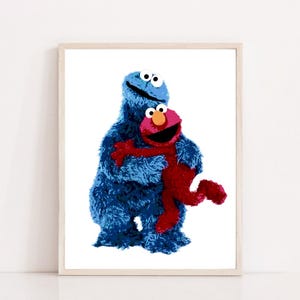 May include: A framed print featuring the Cookie Monster hugging Elmo. The Cookie Monster is a vibrant blue, while Elmo is a bright red. The artwork is set against a white background, creating a cheerful and colorful image.