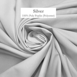 a close-up view of a crumpled, gray fabric, possibly silk or polyester, with a label indicating it is 100% polyester.