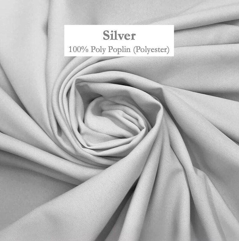 a close-up view of a crumpled, gray fabric, possibly silk or polyester, with a label indicating it is 100% polyester.