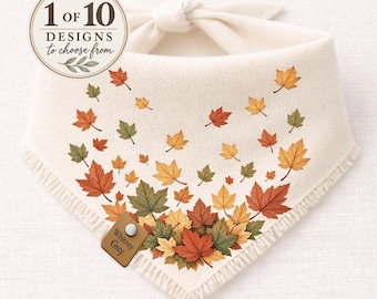 May include: A cream-coloured triangular pet bandana featuring a pattern of scattered autumn maple leaves in shades of orange, yellow, and green. The fabric has a fringed edge and a small brown leather tag labelled Whitney Grey. Text reads 1 of 10 DESIGNS.