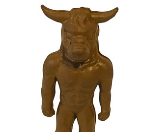 Può includere: Una statuetta di plastica marrone di un minotauro, una creatura mitologica con la testa di un toro e il corpo di un umano.