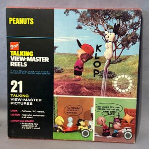 May include: A vintage Peanuts Talking View-Master Reels box. The box features images of Charlie Brown, Snoopy, and other Peanuts characters. The box has the text "PEANUTS", "TALKING VIEW-MASTER REELS", and "21 TALKING VIEW-MASTER PICTURES".