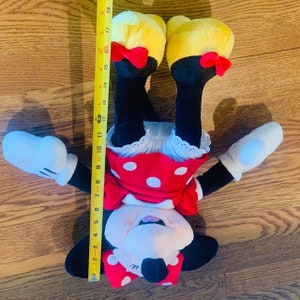 May include: A plush Minnie Mouse toy with red and white polka dot dress, yellow shoes, and black bow. The toy is approximately 18 inches tall.