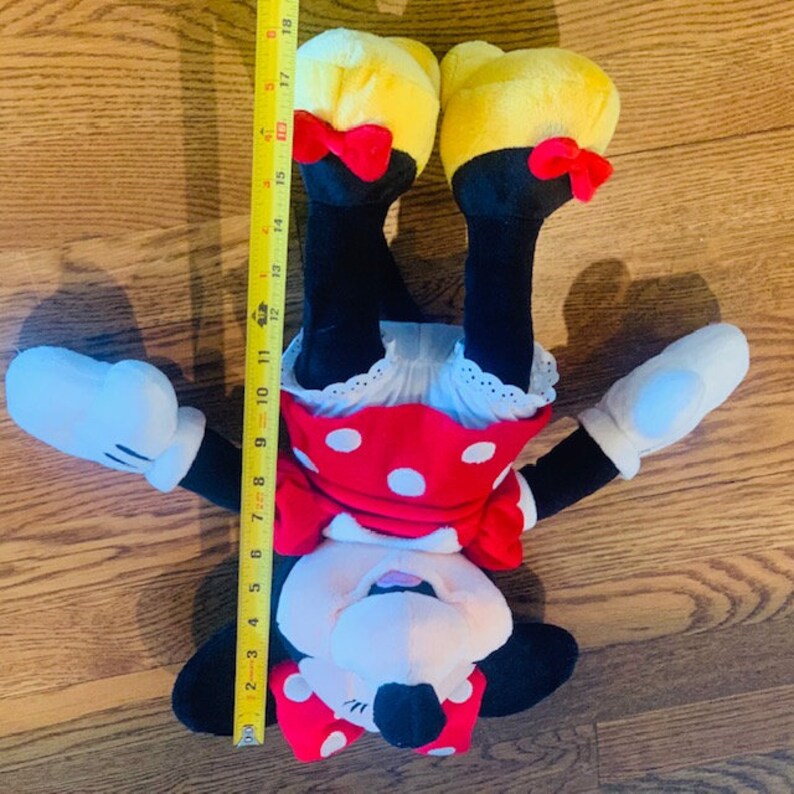 May include: A plush Minnie Mouse toy with red and white polka dot dress, yellow shoes, and black bow. The toy is approximately 18 inches tall.