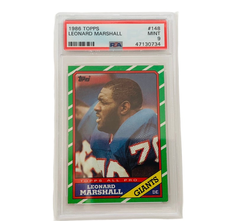 Op de afbeelding: Een 1986 Topps voetbalkaart met Leonard Marshall, een defensive end voor de New York Giants. De kaart is beoordeeld met een 9 door PSA en heeft een groene achtergrond met een witte rand.