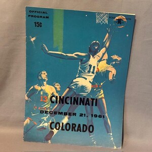 Könnte beinhalten: Vintage Basketball-Programm-Cover mit türkisblauem Hintergrund und Illustrationen von Basketballspielern in Aktion. Der Cover enthält den Text "Cincinnati Colorado" und "Dezember 21, 1961". Das Programm ist mit "Offizielles Programm" gekennzeichnet und kostet 15¢.